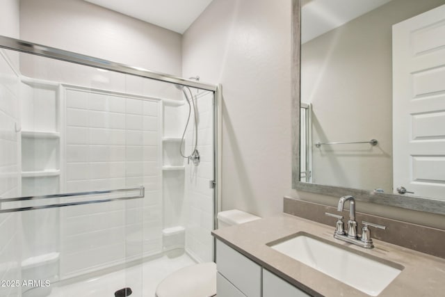 bathroom with toilet, vanity, and a shower with shower door