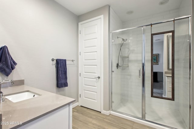 bathroom featuring wood-type flooring, an enclosed shower, and vanity