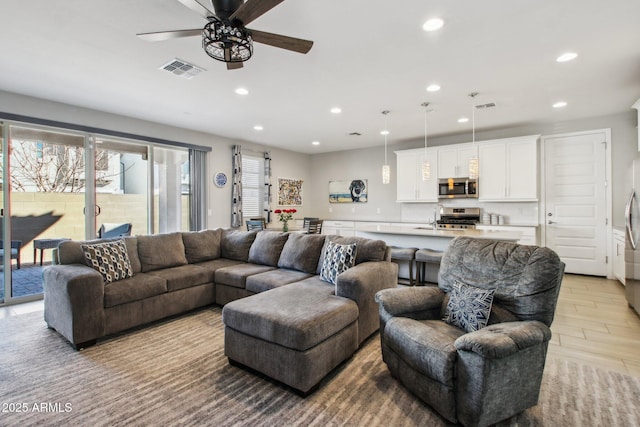 living room with light hardwood / wood-style flooring, ceiling fan, and sink