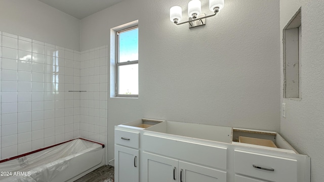 full bathroom with a textured wall and vanity