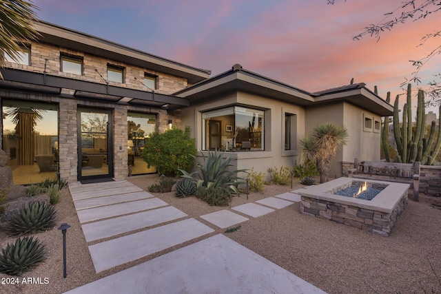 back house at dusk featuring an outdoor fire pit