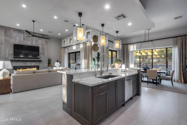 kitchen with light stone countertops, a healthy amount of sunlight, sink, and hanging light fixtures