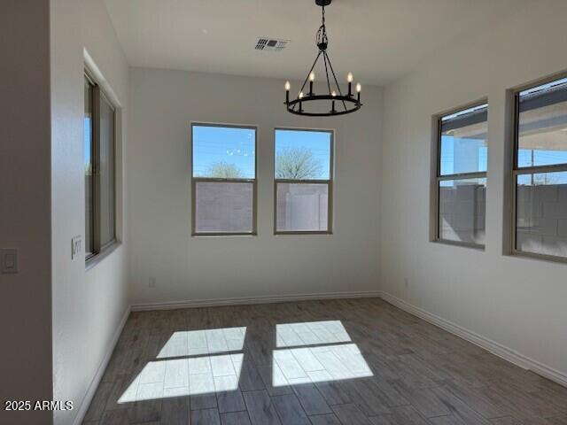 spare room with dark wood-style floors, baseboards, and an inviting chandelier