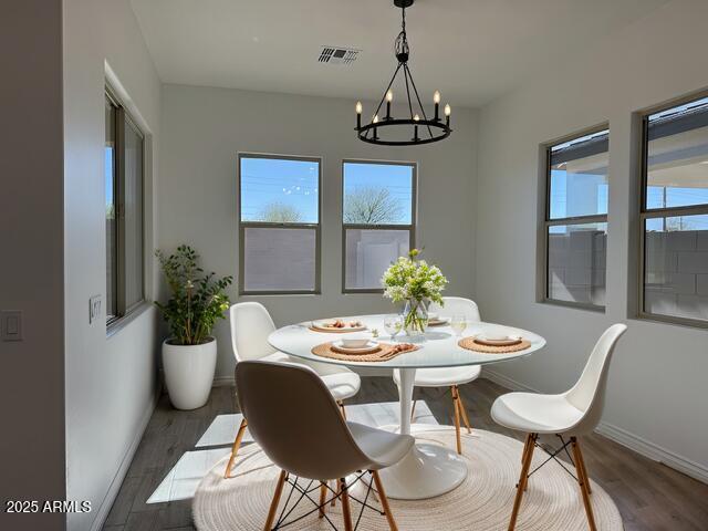 dining room with a notable chandelier, visible vents, baseboards, and dark wood-style flooring