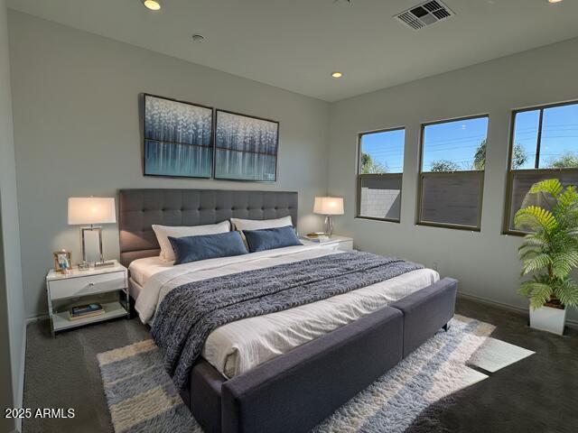 bedroom with multiple windows, dark carpet, and visible vents