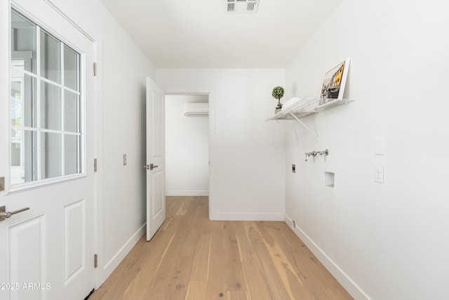 washroom featuring electric dryer hookup, washer hookup, light wood finished floors, a wall unit AC, and baseboards
