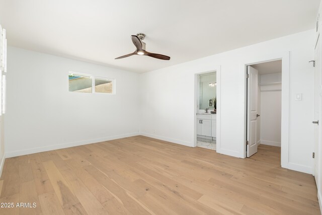unfurnished bedroom with light wood-style floors, a spacious closet, and baseboards