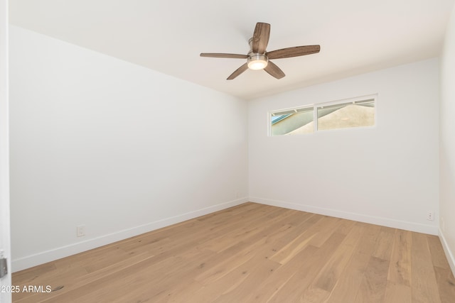 spare room featuring baseboards, light wood finished floors, and ceiling fan