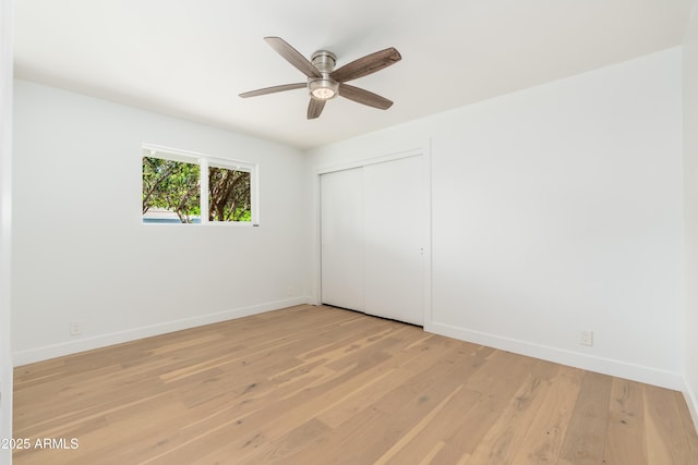 unfurnished bedroom featuring light wood-style floors, baseboards, a closet, and a ceiling fan