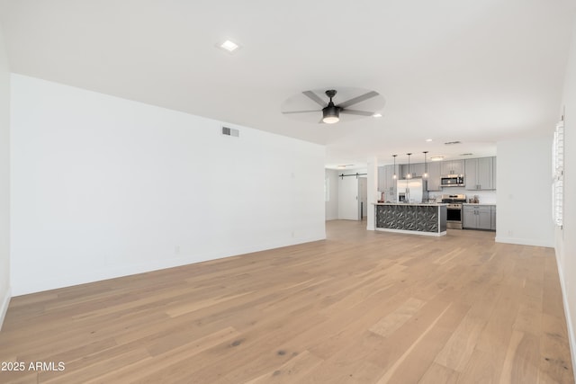 unfurnished living room featuring ceiling fan, light wood-style flooring, baseboards, and recessed lighting