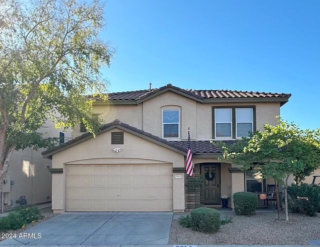 view of front of home with a tile roof, a garage, driveway, and stucco siding