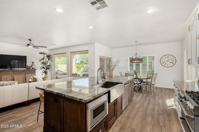 kitchen featuring appliances with stainless steel finishes, a sink, visible vents, and light wood-style floors