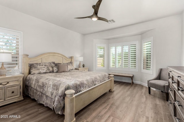 bedroom featuring a ceiling fan, baseboards, visible vents, and wood finished floors