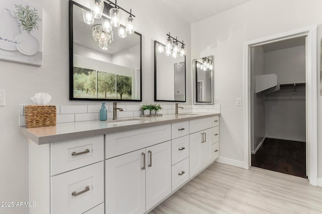 full bathroom featuring double vanity, baseboards, backsplash, and a sink