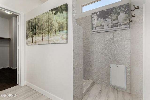 bathroom with a walk in shower, wood finished floors, and baseboards