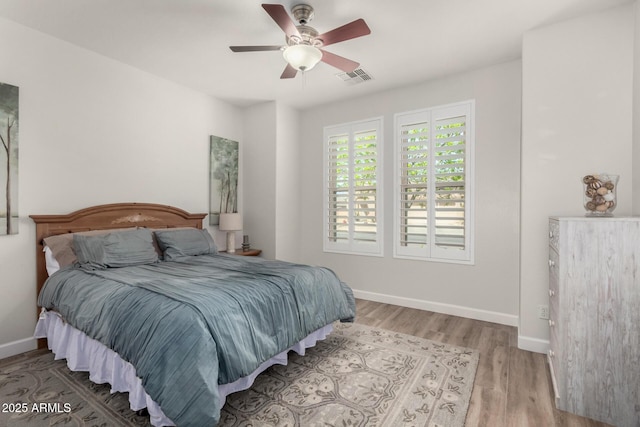 bedroom with a ceiling fan, wood finished floors, visible vents, and baseboards