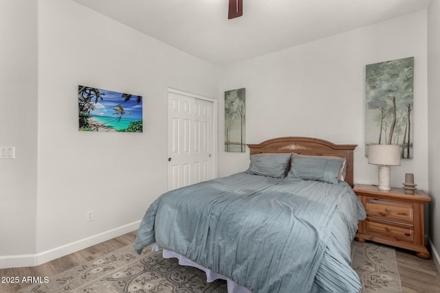 bedroom featuring a closet, wood finished floors, a ceiling fan, and baseboards