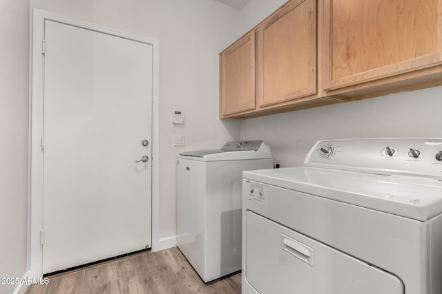 washroom featuring cabinet space, light wood-style flooring, and washing machine and clothes dryer