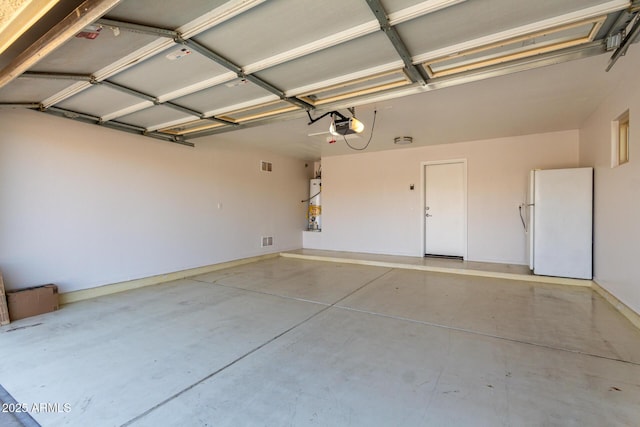 garage featuring visible vents, water heater, freestanding refrigerator, and a garage door opener