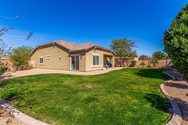 rear view of property with a yard, a fenced backyard, a tiled roof, and stucco siding