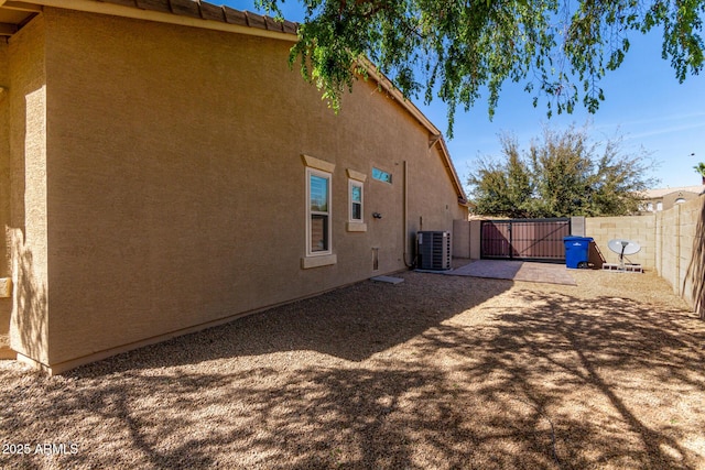 back of property featuring central air condition unit, a gate, fence, and stucco siding