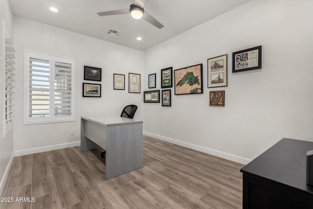 office space with visible vents, baseboards, a ceiling fan, and wood finished floors