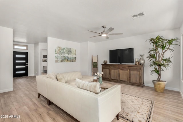 living room featuring light wood finished floors, baseboards, visible vents, and a ceiling fan