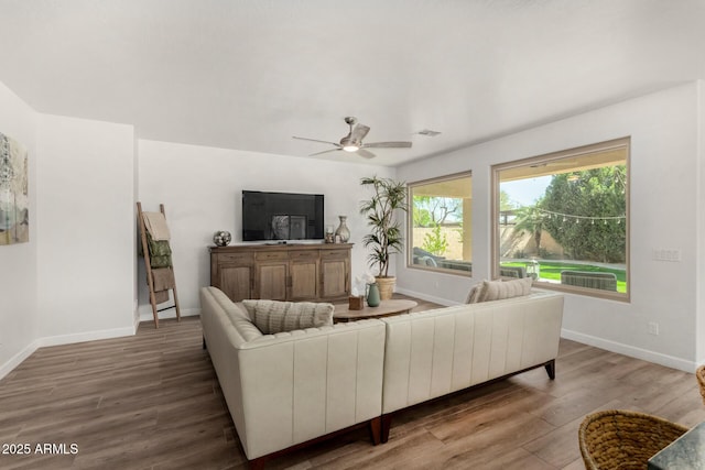 living area featuring a ceiling fan, visible vents, baseboards, and wood finished floors