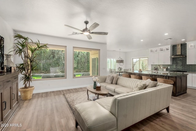 living room with recessed lighting, baseboards, visible vents, and light wood finished floors