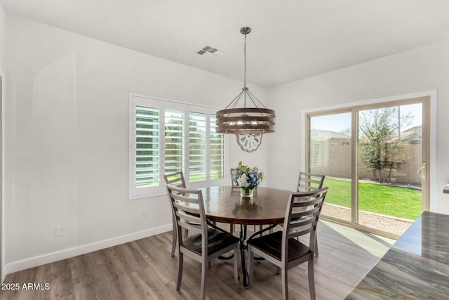 dining area featuring baseboards, wood finished floors, visible vents, and a healthy amount of sunlight