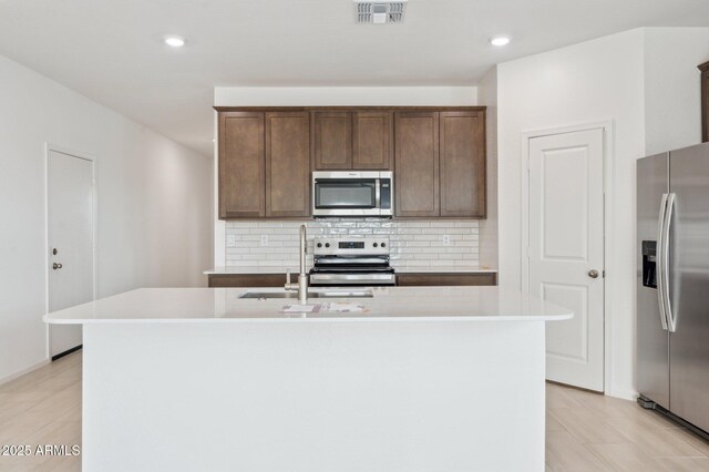 25425 W Graham Trl, Buckeye, AZ 85326 - kitchen with visible vents, a sink, appliances with stainless steel finishes, an island with sink, and backsplash