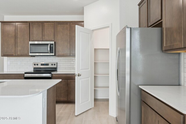 25425 W Graham Trl, Buckeye, AZ 85326 - kitchen featuring dark brown cabinetry, decorative backsplash, light countertops, and stainless steel appliances