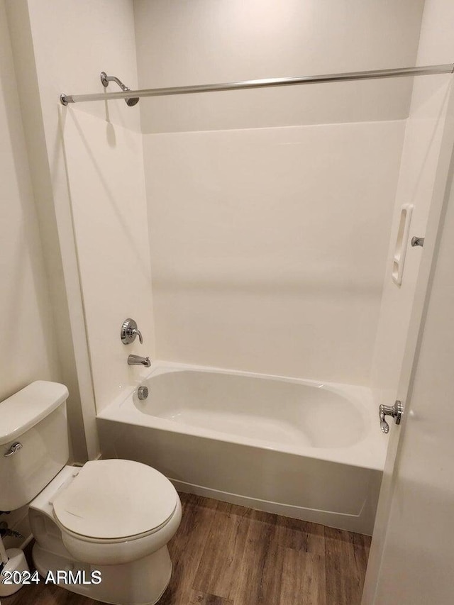 bathroom with hardwood / wood-style flooring, bathing tub / shower combination, and toilet