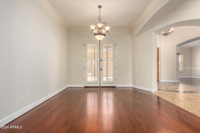 spare room featuring wood-type flooring, crown molding, and a notable chandelier