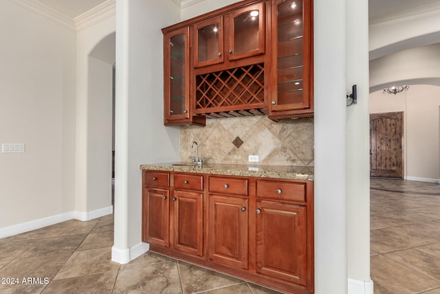 bar with tile patterned flooring, sink, light stone counters, crown molding, and decorative backsplash