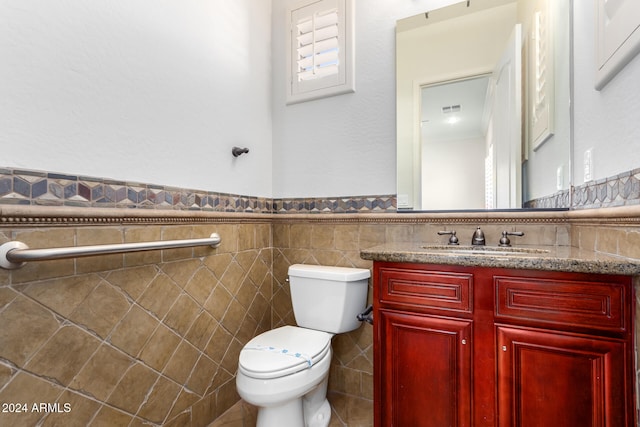 bathroom with vanity, toilet, and tile walls