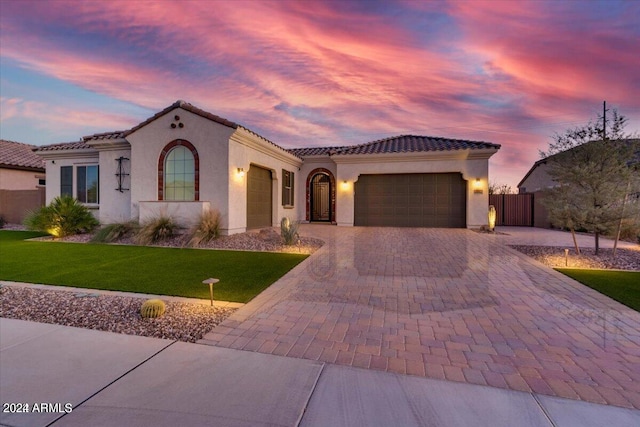 mediterranean / spanish-style home with a lawn and a garage