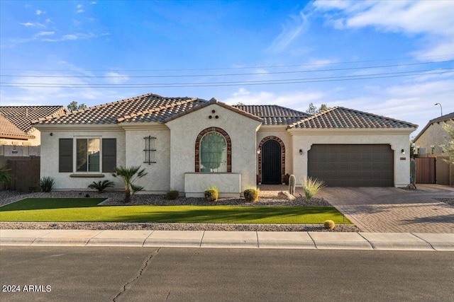 mediterranean / spanish house with a garage and a front lawn