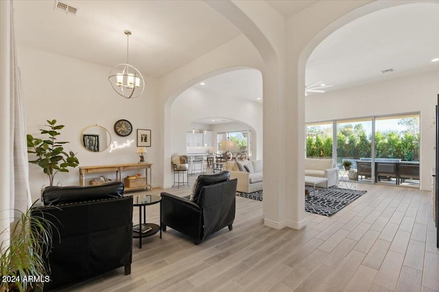 living room with ceiling fan with notable chandelier and light hardwood / wood-style flooring