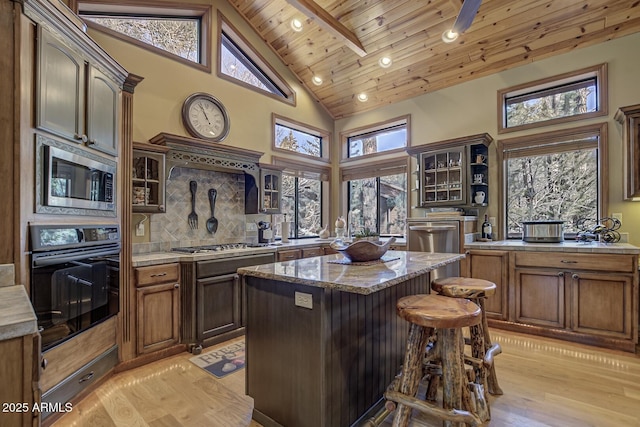 kitchen with wood ceiling, glass insert cabinets, appliances with stainless steel finishes, and light wood-style flooring