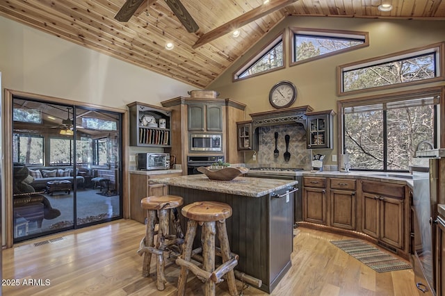 kitchen with high vaulted ceiling, oven, wood ceiling, stainless steel microwave, and a center island