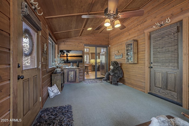 carpeted foyer with ceiling fan, wooden ceiling, wood walls, and vaulted ceiling