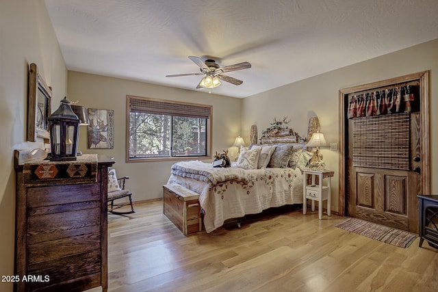 bedroom with light wood finished floors, a textured ceiling, and a ceiling fan