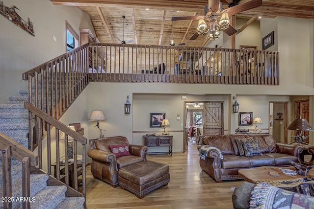 living area featuring beam ceiling, wood finished floors, wooden ceiling, a healthy amount of sunlight, and ceiling fan