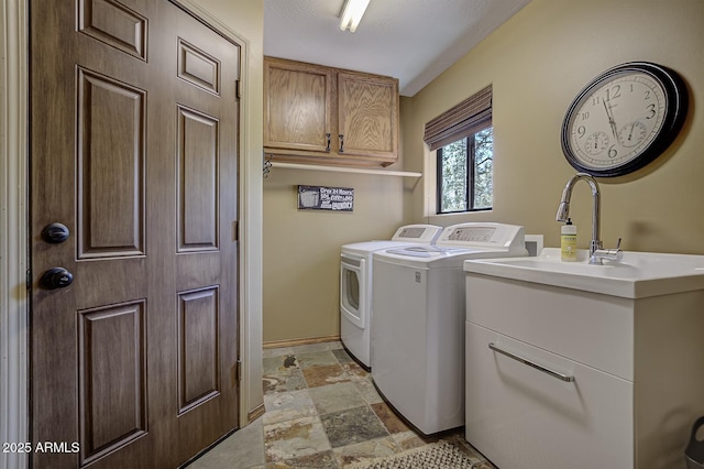 washroom featuring cabinet space, stone tile floors, and washer and clothes dryer