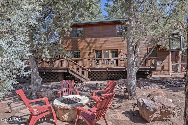 back of house featuring a wooden deck, a fire pit, and stairs