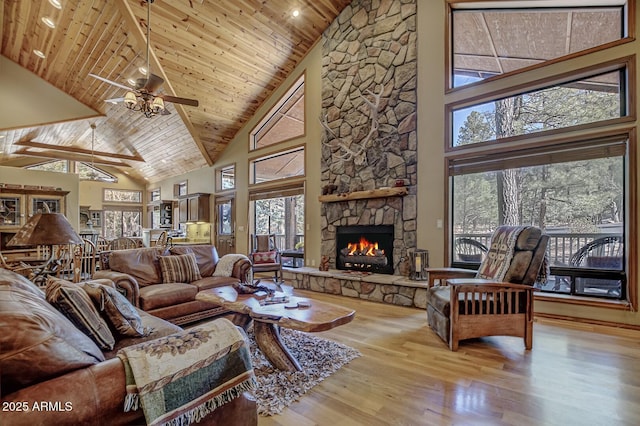 living area featuring ceiling fan, wood ceiling, a fireplace, wood finished floors, and high vaulted ceiling