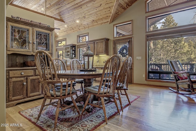 dining room with wooden ceiling, a wealth of natural light, and high vaulted ceiling