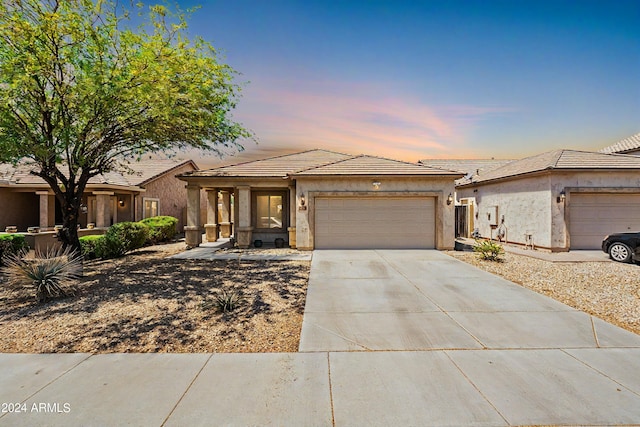 view of front of property with driveway, an attached garage, a tiled roof, and stucco siding