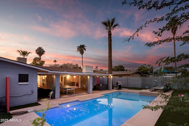 pool at dusk featuring an outdoor living space and a patio area